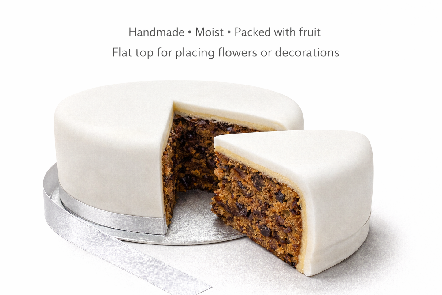 sliced 8 inch iced wedding fruit cake showing marzipan layer and rich fruit interior with silver ribbon base