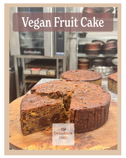 Vegan fruit cake on a wooden board with 'Grandpa's Cakes' branding in a bakery setting.